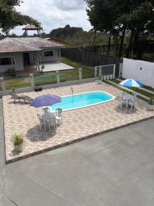 einen Pool mit 2 Sonnenschirmen sowie 2 Tischen und Stühlen in der Unterkunft Asas da Maré Pousada in Bragança