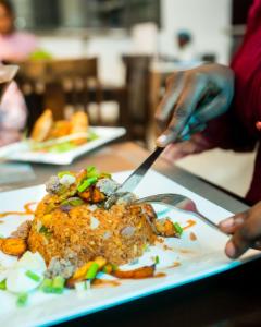 una persona che taglia un piatto di cibo su un tavolo di Las Vegas Beach Resort And Hotel a Fete 1 altra foto