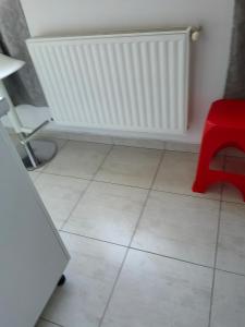 home stay في Ghanpokhara: غرفة بها كرسي أحمر ومبرد