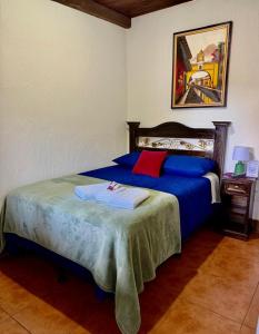 1 dormitorio con 1 cama con almohadas azules y rojas en Hotel Casa Jasmin, en Antigua Guatemala