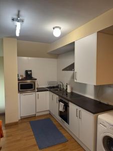 a kitchen with white cabinets and black counter tops at Ático luminoso en Felechosa in Felechosa
