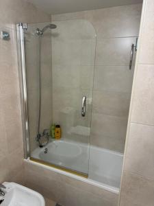 a bathroom with a shower with a tub and a sink at Ático luminoso en Felechosa in Felechosa