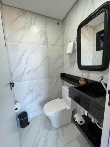 a bathroom with a toilet and a sink and a mirror at Apartamento Texas in Pomerode +12 photos