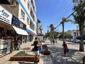 a group of people walking down a city street at Com churrasqueira em Canasvieiras in Florianópolis