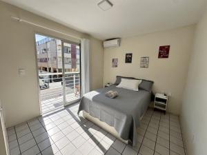 a bedroom with a bed and a large window at Com churrasqueira em Canasvieiras in Florianópolis