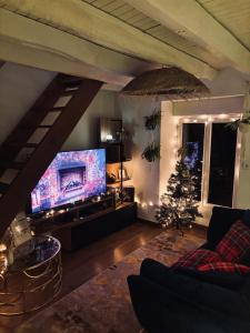 a living room with a large tv and a christmas tree at PrestigeLodgesFontainebleau, Maison polynésienne & jacuzzi privé in Pamfou +31 photos