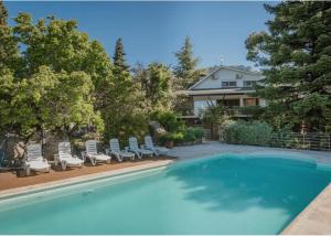 a swimming pool with lounge chairs and a house at Villa Karina in Valdemanco