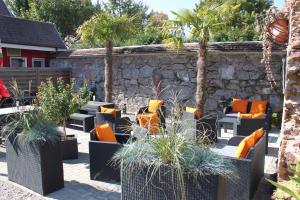 un patio con sofás, palmeras y una pared de piedra. en Hotel Restaurant Hochdorfer Hirschen, en Freiburg im Breisgau