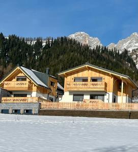 una gran casa de madera con nieve delante en Ferienhaus Korda, en Ramsau am Dachstein