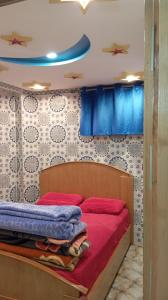 a bedroom with a bed with red sheets and blue curtains at Dar Bouchikhi in Moulay Yacoub +4 photos