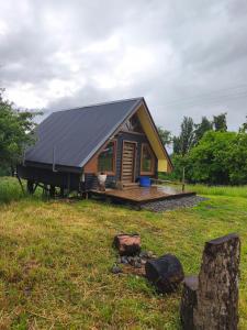 a small house with a black roof on a field at Cabaña fundo Mohr in Pichil