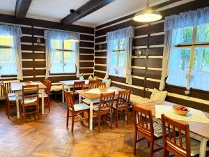 a restaurant with wooden tables and chairs and windows at Chata Amálka in Rokytnice nad Jizerou