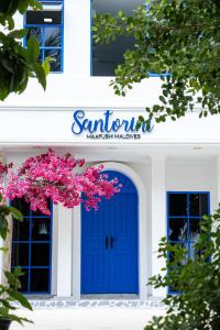 a blue door on a white building with pink flowers at Santorini Maafushi Maldives in Maafushi