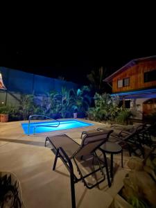 Villas Solar في شاطئ سانتا تيريزا: مجموعة كراسي ومسبح في الليل