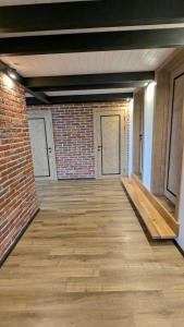 una stanza vuota con un muro di mattoni e pavimenti in legno di GORF House a Krapivnik