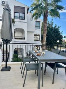 a table with chairs and an umbrella on a balcony at Oleza Sun Playa Flamenca in Playa Flamenca