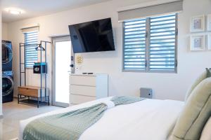 Un dormitorio con una cama blanca y un televisor de pantalla plana. en Aquaville Dorado Moderna Studio 6, en Dorado