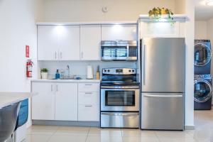 eine Küche mit weißen Schränken und einem Edelstahlkühlschrank in der Unterkunft Aquaville Dorado Moderna Studio 6 in Dorado