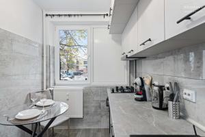een witte keuken met een tafel en een raam bij Stylish Blue Haven 1 BR Balcony Access in Boekarest