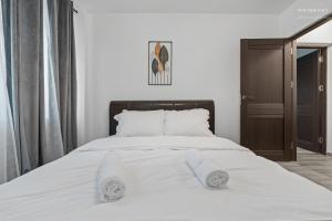 een wit bed met twee witte handdoeken erop bij Stylish Blue Haven 1 BR Balcony Access in Boekarest