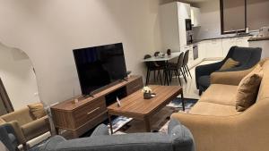 a living room with couches and a television and a table at The Pearl villa sifah muscat in As Sīfah