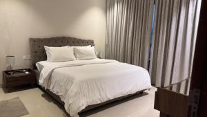 a bedroom with a bed with white sheets and a window at The Pearl villa sifah muscat in As Sīfah