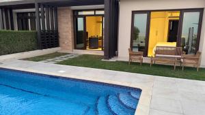 a swimming pool in front of a house at The Pearl villa sifah muscat in As Sīfah +2 photos