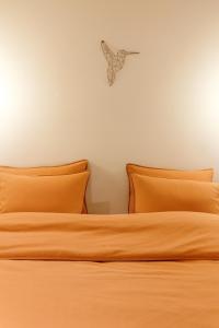 a bed with two orange pillows in a room at Au nid du colibri in Somme-Leuze
