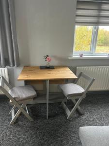 a wooden table with two chairs and a vase with flowers on it at Happy Airfield Studio in Sandtoft