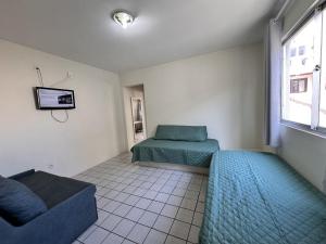 a room with two beds and a couch and a tv at Com churrasqueira em Canasvieiras in Florianópolis