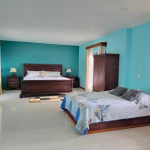 蒙泰韦尔德哥斯达黎加Monteverde House的一间卧室，有两张床和一面蓝色的墙