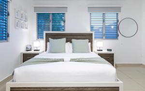 Un dormitorio blanco con una cama grande con persianas azules. en Aquaville Dorado Moderna Studio 6, en Dorado