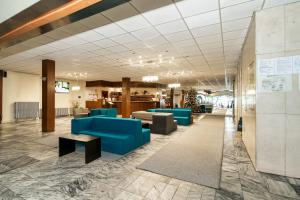 eine Lobby mit blauen Stühlen und Tischen in einem Gebäude in der Unterkunft Hotel Slovakia in Žilina