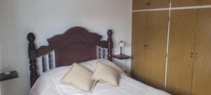 uma cama com cabeceira de madeira e dois travesseiros em 4 Mares em Punta del Este