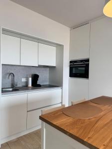 a kitchen with white cabinets and a wooden counter top at Studio in Wenduine with frontal sea view in Mellet