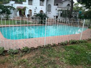 a fence around a swimming pool in front of a house at Borrowdale Hearthside Retreat in Harare