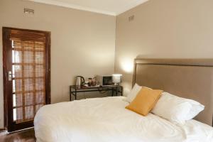 a bedroom with a white bed with a pillow on it at Borrowdale Hearthside Retreat in Harare