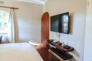 a bedroom with a bed and a flat screen tv on a wall at Borrowdale Hearthside Retreat in Harare