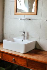 a white sink on a wooden counter with a mirror at Borrowdale Hearthside Retreat in Harare