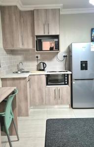 a kitchen with wooden cabinets and a stainless steel refrigerator at Ekuhlaleni Room 6 in Pretoria