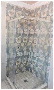 a shower in a bathroom with a floral wallpaper at Ekuhlaleni Room 6 in Pretoria +6 photos