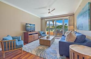 a living room with a blue couch and a tv at Honua Kai Konea 206 in Lahaina