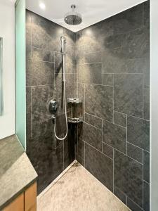 a bathroom with a shower with black tiles at Luxuriöses Penthouse in Davos modern hochwertig in Davos
