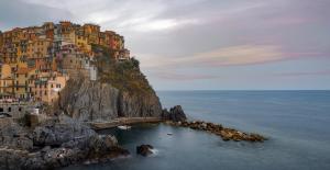 a building on the side of a mountain in the water at The Sea View Attic in Manarola