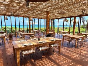 a restaurant with wooden tables and chairs and the ocean at Windward Mayreau Resort in Mayreau