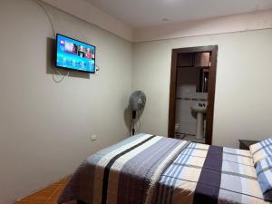 a bedroom with a bed and a flat screen tv on the wall at Hostal Muchik in Chiclayo
