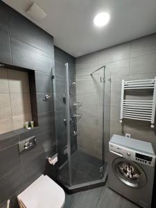 a bathroom with a shower and a washing machine at Ameri Plaza Lilu Home apartment in Tbilisi City