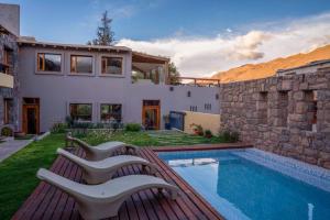 a house with a swimming pool and two benches at KALLPA WARMI Hotel Panoramico in Tilcara