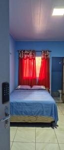 een slaapkamer met een bed met rode gordijnen en een raam bij Casa do ViajanteBr in Barreirinhas