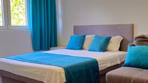 a bedroom with two beds with blue curtains and a couch at Zero Distance Studio in Podgorica +7 photos